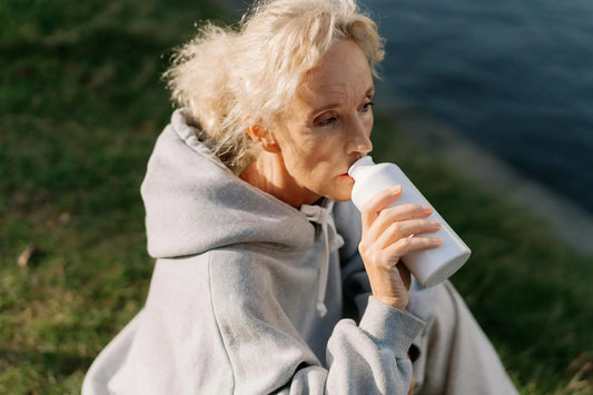 Old lady drinking from a white water bottle